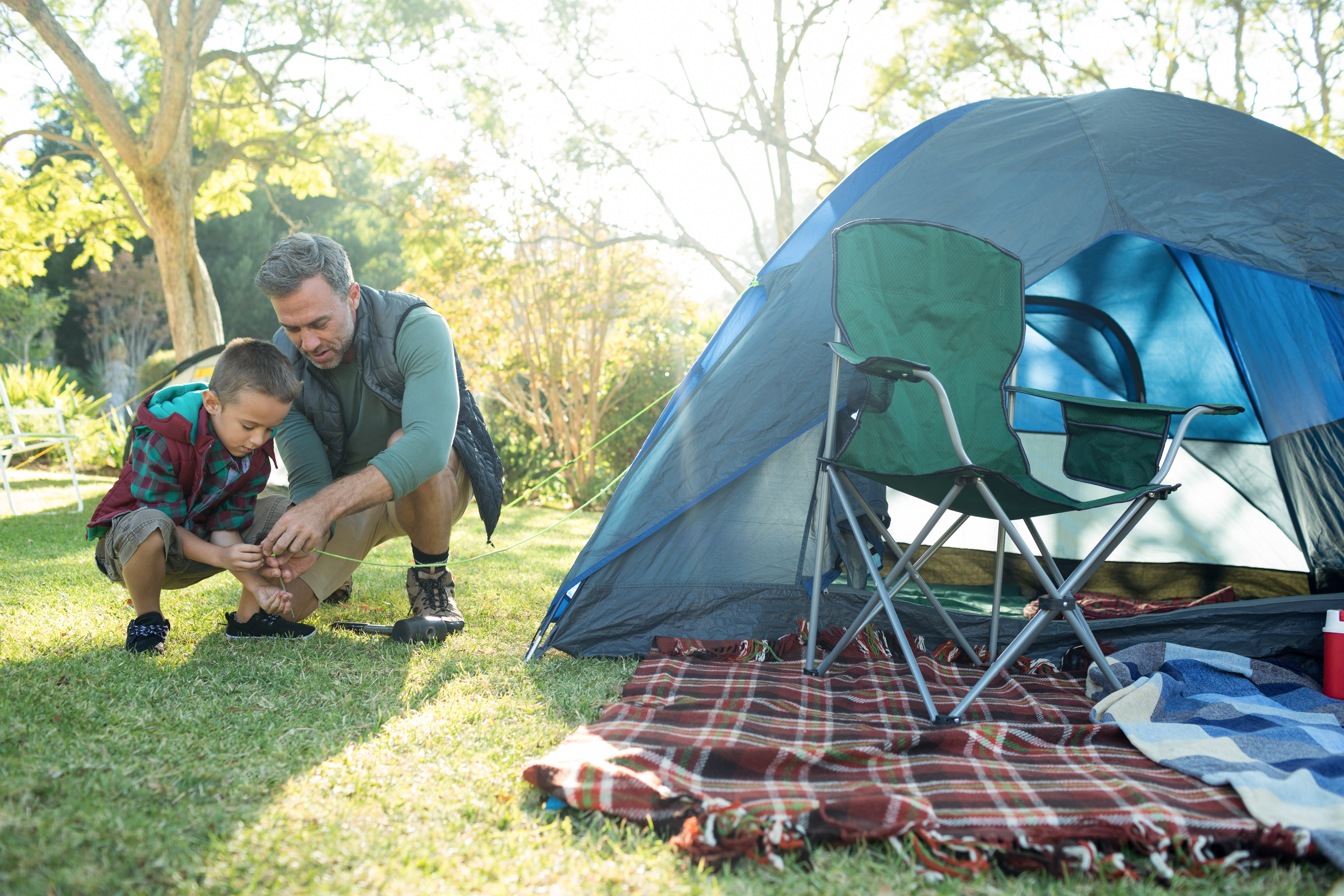 Campers near a tent and fire in an outdoor setting